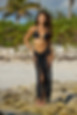 Image of a woman in a stylish black sarong skirt with playful fringe accents, embodying beachside elegance. This versatile piece works as both a chic fringe beach cover-up and a sleek fringe bathing suit cover-up. The sarong's tassel detailing adds a touch of flair, making it a fashionable option for those seeking a black tassel sarong. Its adaptable design can also transform into a trendy fringe cover-up dress, making it perfect for beachside strolls or poolside relaxation. With a sheer black sarong like this, you can effortlessly elevate your poolside ensemble. Whether you're looking for the best sarong cover-up or a sexy beach sarong, this piece offers style and function. Discover a world of pool sarong beauty and enhance your beachwear collection with this sophisticated swim sarong skirt
